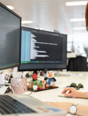 A woman works at a computer and writes program code.