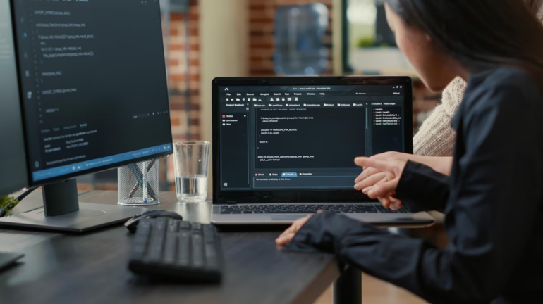 a woman is sitting in the office using a notebook and computer coding