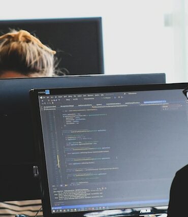 man in black shirt sitting beside black flat screen computer monitor