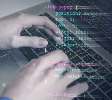 Hands writing program code on a laptop