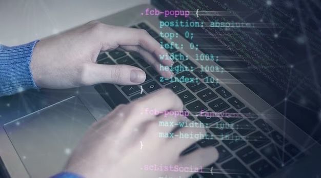 Hands writing program code on a laptop